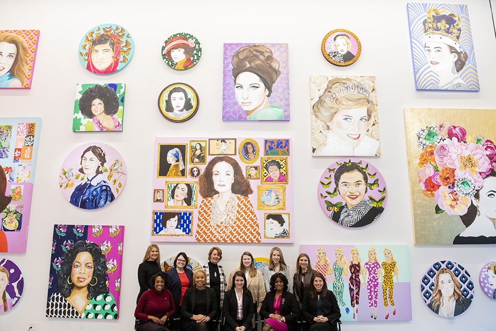 MBA scholarship announcement: photo of Brenau University's Inaugural Cohort of the Executive Women's MBA, posed in front of color portraits by Ashley Longshore at Diane von Furstenberg's NYC Studio